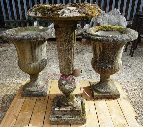 Garden statuary comprising; a pair of early 20th century stone urns of tapering form, 48cm wide x 60cm high and a stone bird bath on fluted column and