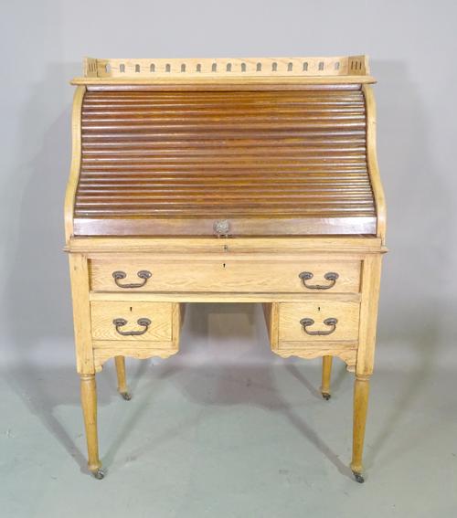 An Edwardian oak roll top desk with tambour front over one long and two short drawers on tapering supports 91cm wide x 128cm high.  K7
