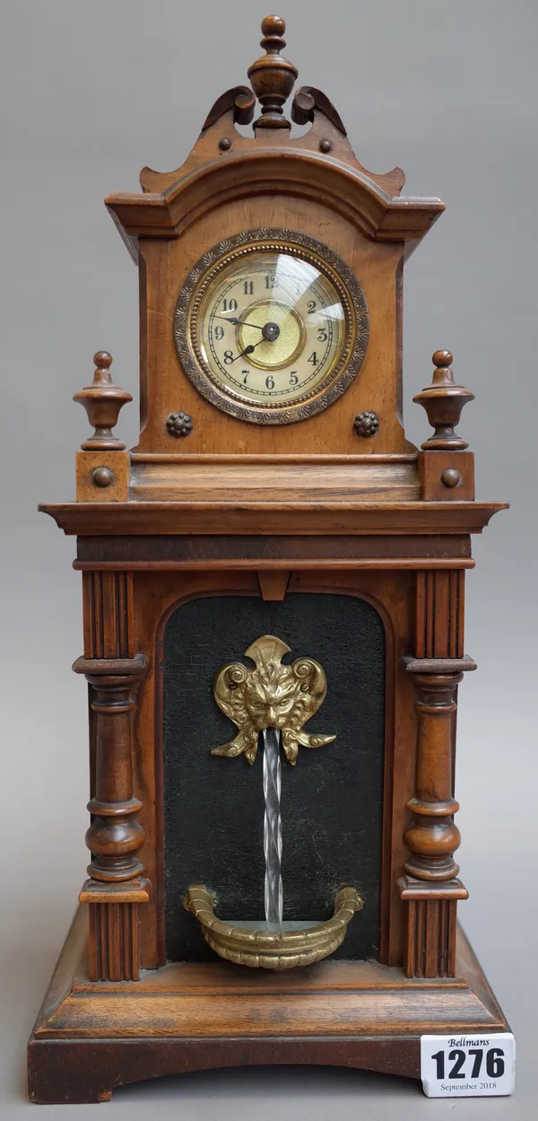 A Black Forest novelty mantel clock, early 20th century, the arched hood enclosing dial and movement over a body with automaton wall fountain, 35cm hi