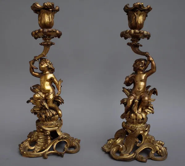 A pair of late 19th century gilt bronze figural candlesticks, each centred with a putto over a foliate pierced base (30cm high) and a pair of porcelai
