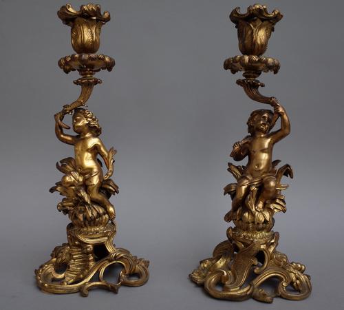 A pair of late 19th century gilt bronze figural candlesticks, each centred with a putto over a foliate pierced base (30cm high) and a pair of porcelai