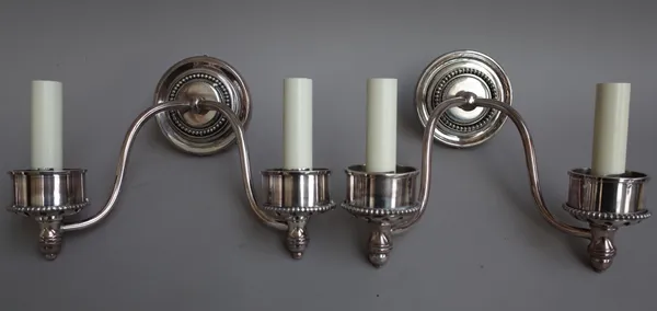 A set of four silvered metal two branch wall lights with glass hurricane shades, (4).