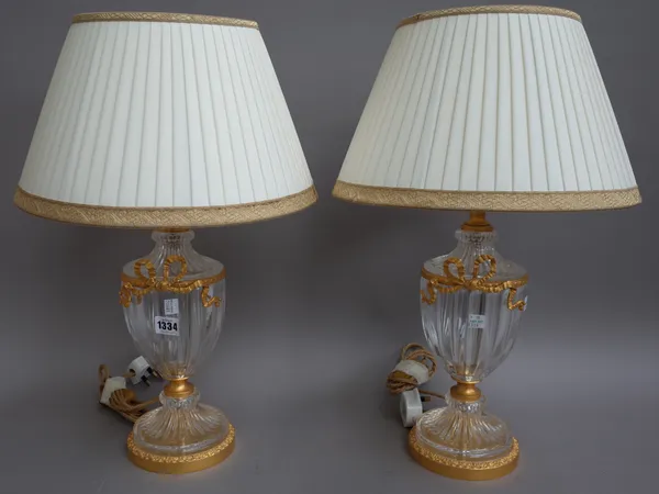 A pair of Victorian style glass and gilt metal mounted urn form table lamps, modern, with tied ribbon embellishments on a circular foot with cream sil