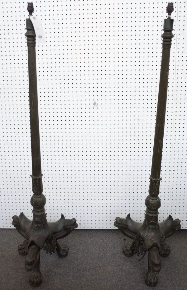 A pair of French cast iron and metal alloy standard lamps, late 19th century, each fluted tapering column over a foliate cast triform base and lion pa
