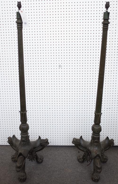 A pair of French cast iron and metal alloy standard lamps, late 19th century, each fluted tapering column over a foliate cast triform base and lion pa