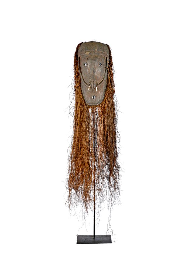 A Magondo tribal wooden mask on stand, Papua New Guinea, with bone decoration through the nose and straw hair displayed on purpose made metal floor st