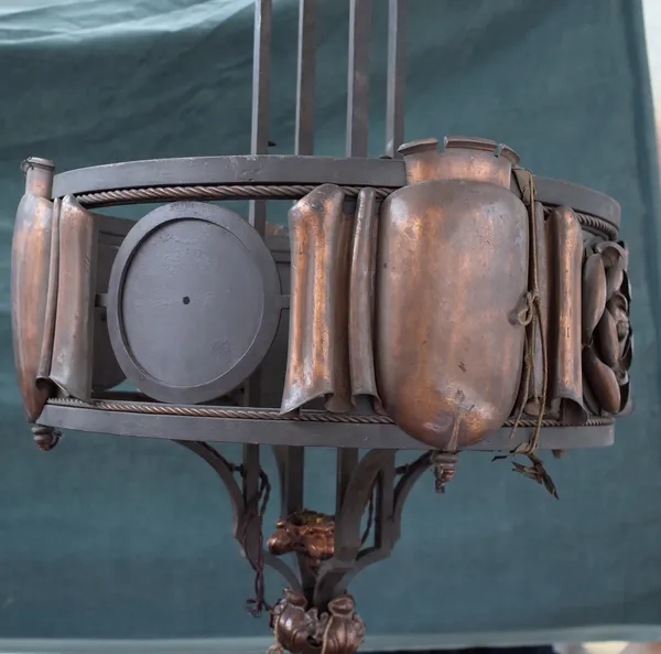 A steel, copper mounted chandelier, early 20th century, of circular form, the plates of scroll form, interspersed with Tudric roses, formerly with han