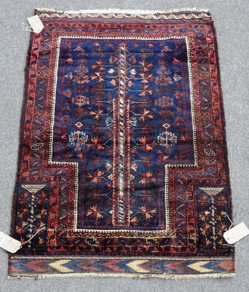 A Beluchistan prayer rug, the indigo mehrab with a tree of life, other flower motifs; plant spandrels; a leaf border, flatweave ends, 132cm x 89cm.