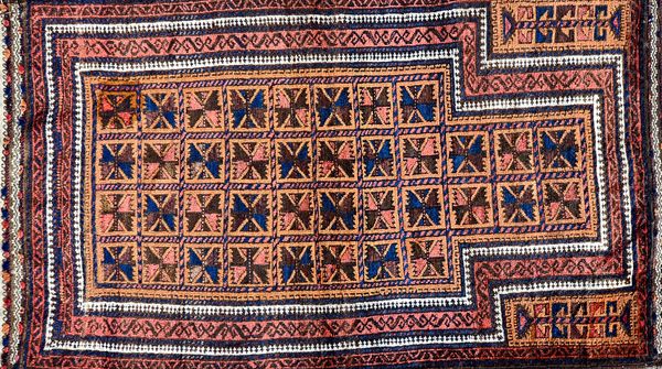 A Beluchistan prayer rug, the pale brown mehrab with squared sections of single flowerheads, supporting spandrels; a madder border, flatweave ends, 15