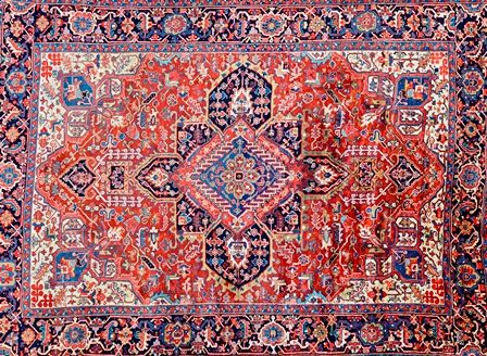 A Heriz carpet, Persian, the madder field with a bold central medallion, ivory spandrels, all with angular floral and leaf sprays, a dark indigo palme