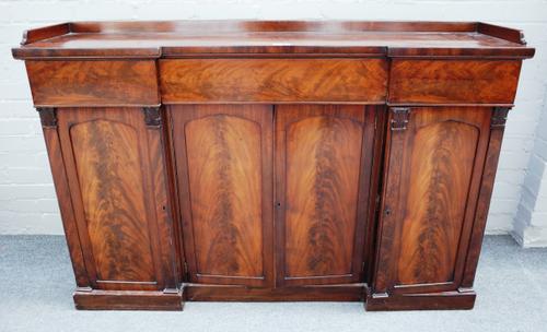 A late Regency mahogany side cabinet, the inverted breakfront top with three flush fit drawers over four panel cupboards on plinth base, 149cm wide x