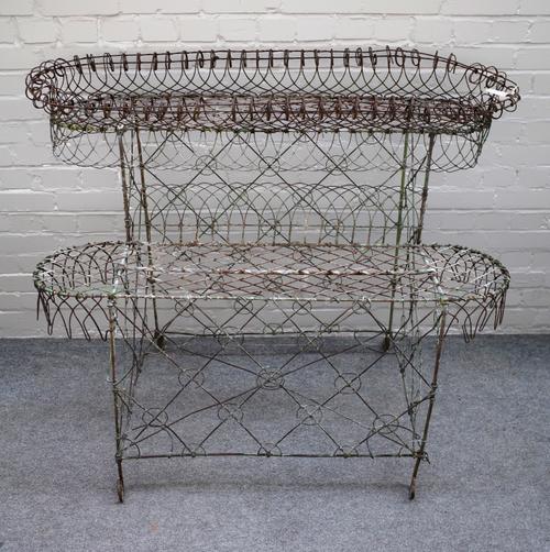 An Edwardian wire work double height oval plant stand, 133cm wide x 103cm high x 63cm deep.