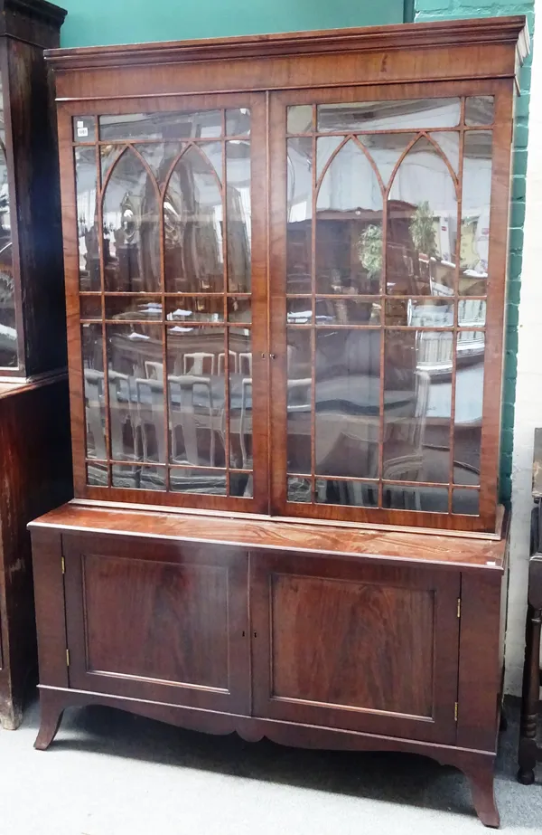 A George III mahogany bookcase display cabinet, the pair of Gothic arch astragal glazed doors over a pair of lower panel cupboards on splayed bracket