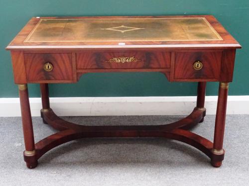 An Empire style gilt metal mounted mahogany writing desk, with three frieze drawers, on turned supports united by an 'X' frame stretcher, 120cm wide x