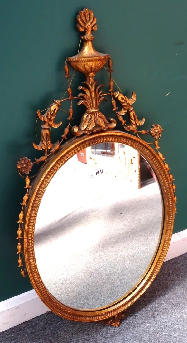 A George III style gilt framed oval mirror, with floral draped urn crest, 55cm wide x 100cm high.