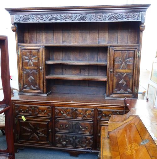 An 18th century and later oak dresser, the enclosed three tier plate rack with integral cupboards over four drawers and further pair of cupboards all