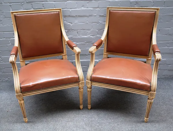 A pair of Louis XVI style cream painted open armchairs on tapering fluted supports, 60cm wide x 91cm high (2).
