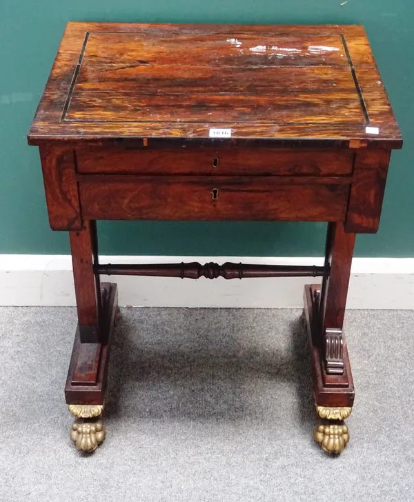 A William IV rosewood work table, with rectangular lift top over single drawer, on trestle end standards, and four carved and gilded lion's paw feet,