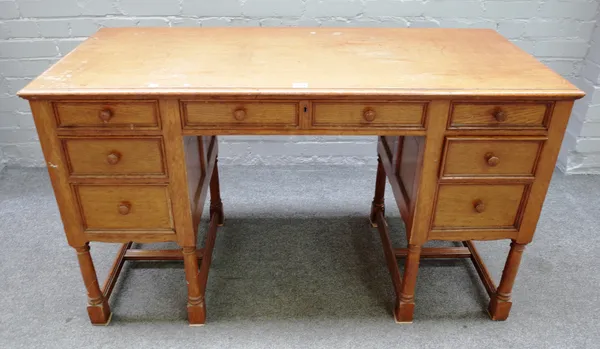 An early 20th century oak writing desk with seven drawers about the knee on turned supports, 125cm wide x 73cm high x 56cm deep.