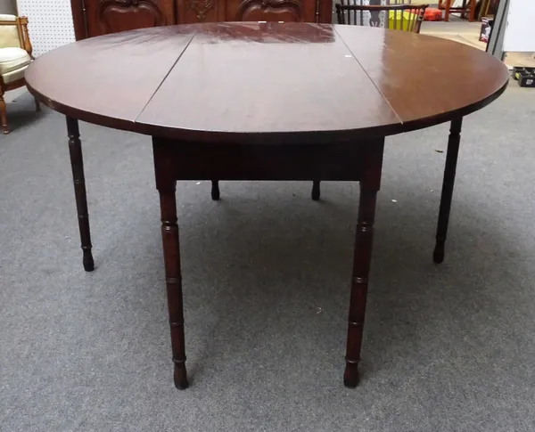 A Regency mahogany dining table, the oval drop flap top on ring turned supports, 56cm cross x 135cm across open x 74cm high x 168cm along.