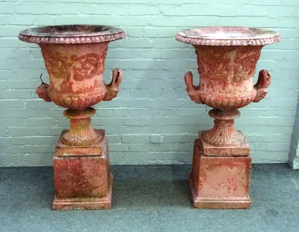 A pair of red glazed reconstituted stone, twin handled garden urns on square pedestals, 65cm diameter x 115cm high (2).