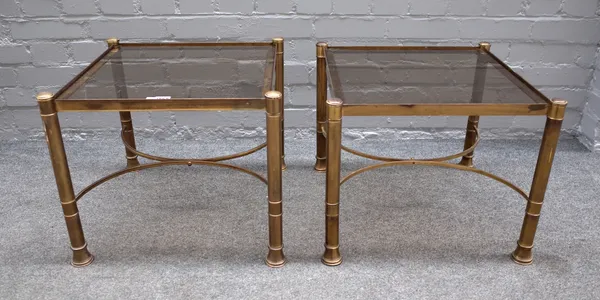 A pair of mid-20th century lacquered brass and smoked glass occasional tables, on turned supports, united by 'X' frame stretchers, 50cm wide x 42cm hi