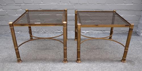 A pair of mid-20th century lacquered brass and smoked glass occasional tables, on turned supports, united by 'X' frame stretchers, 50cm wide x 42cm hi