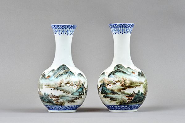 A pair of Chinese porcelain bottle vases, 20th century, possibly Republican, each painted with an extensive landscape between blue enamel borders, iro