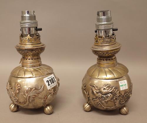 A pair of plated Asian table lamps, each base of spherical form, decorated with a dragon and raised on three melon form feet and further plated wares,