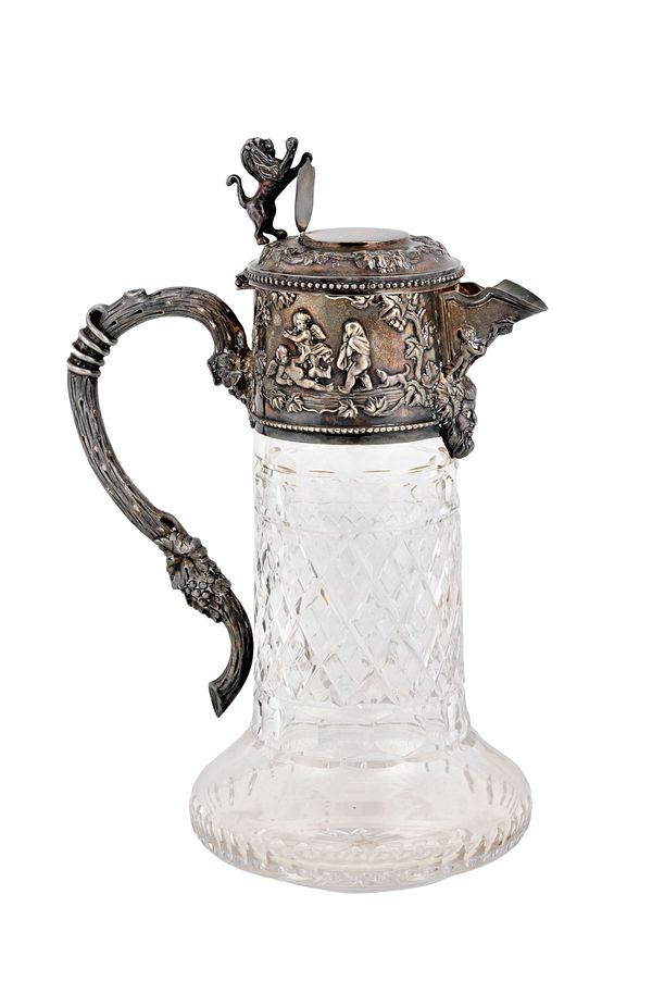 A silver mounted faceted glass claret jug, the mount decorated with cherubs, the thumbpiece with a lion surmount, the handle of rustic form with fruit