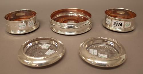 A pair of silver mounted bottle coasters, with turned wooden bases, diameter 9.5cm, a silver mounted larger bottle coaster, with a turned wooden base,