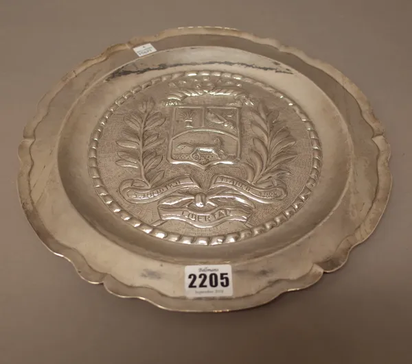 A South American silver shaped circular dish, probably Venezuelan, commemorating independence, the centre decorated with a shield, a motto, foliate sp