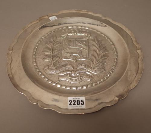 A South American silver shaped circular dish, probably Venezuelan, commemorating independence, the centre decorated with a shield, a motto, foliate sp