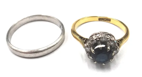 A gold and platinum, sapphire and diamond cluster ring, claw set with the circular cut sapphire at the centre, in a surround of eight circular cut dia