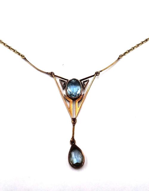 An aquamarine two stone pendant necklace, in a pierced Art Deco geometric design, collet set with an oval cut aquamarine to the centre and with a pear