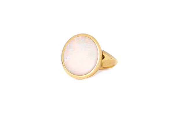 An 18ct gold and opal single stone ring, collet set with an oval opal, otherwise with a textured finish, ring size J and a half, gross weight 5.2 gms.