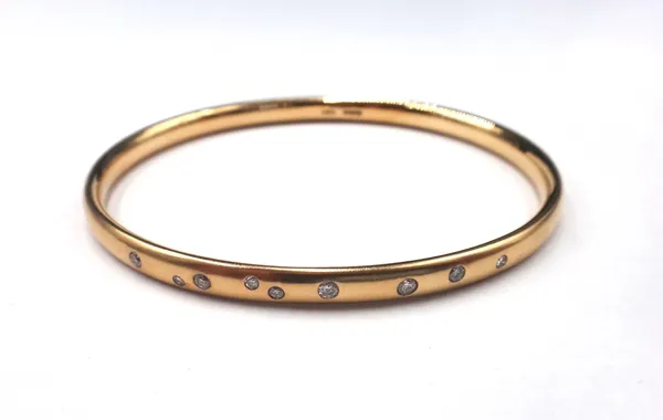 A 9ct gold and diamond set oval bangle, by David Fowkes, mounted with a row of nine circular cut diamonds, in an abstract design, otherwise with a mat