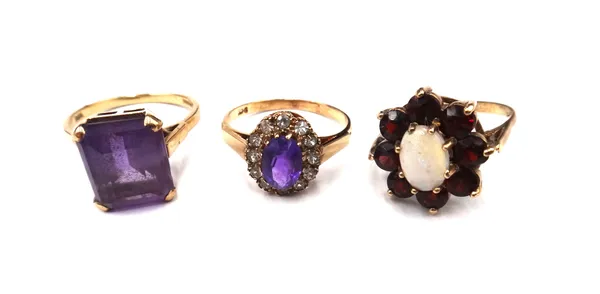 A 9ct gold ring, claw set with a cut cornered rectangular step cut amethyst, a gold, amethyst and colourless gem set oval cluster ring, detailed 9 CT