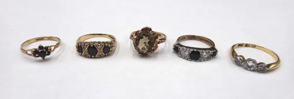 A gold and diamond three stone ring, collet set with a row of cushion shaped diamonds and with the principal diamond mounted at the centre, detailed 1