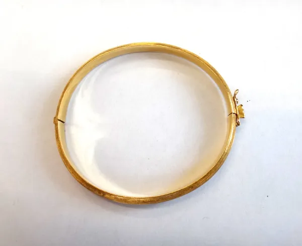A gold oval hinged bangle, having a textured finish, on a snap clasp, with a foldover safety catch, gross weight 11.6 gms.