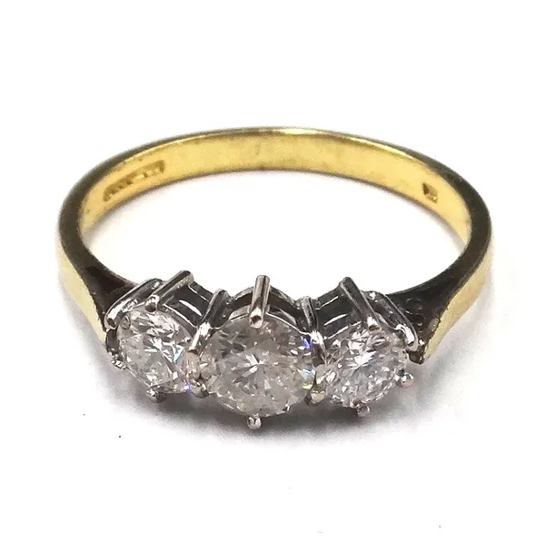 An 18ct gold and diamond set three stone ring, claw set with a row of circular cut diamonds and with the principal diamond mounted to the centre, ring