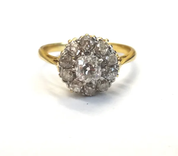 A gold and diamond cluster ring, claw set with the principal cushion shaped diamond at the centre, in a surround of ten smaller cushion shaped diamond
