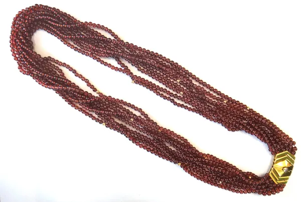 An eight row necklace of garnet beads, on a gold and diamond set single stone clasp, collet set with a cushion shaped diamond, detailed 750.