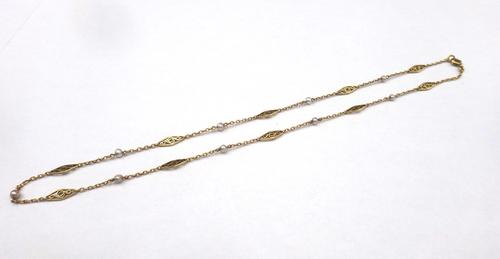 A gold and seed pearl set necklace, circa 1910, in an oval link design, spaced with scroll pierced links, alternating with seed pearls, on a boltring