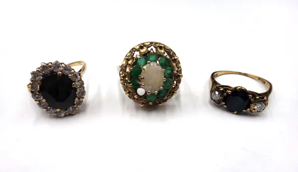 A 9ct gold, opal and emerald set oval cluster ring, (one emerald lacking), a 9ct gold, sapphire and diamond set three stone ring, claw set with the ov