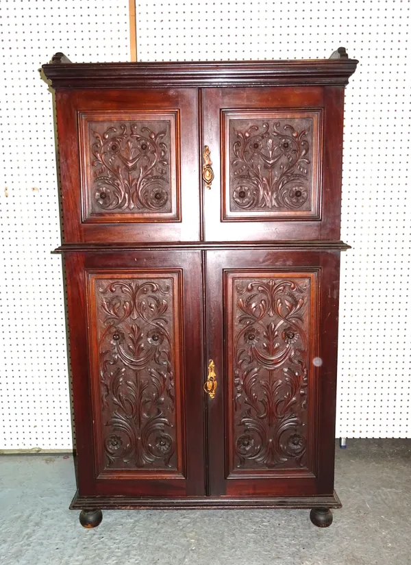 A Victorian mahogany side cabinet with foliate carved panel doors on bun supports, 76cm wide x 137cm high.   H5