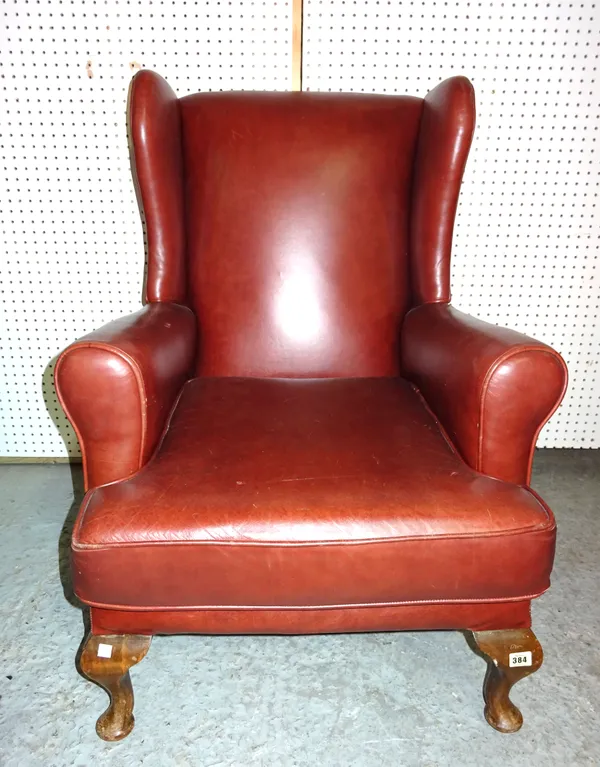 A 20th century mahogany framed wingback armchair with red leather upholstery on tapering cabriole supports, 78cm wide.   E7