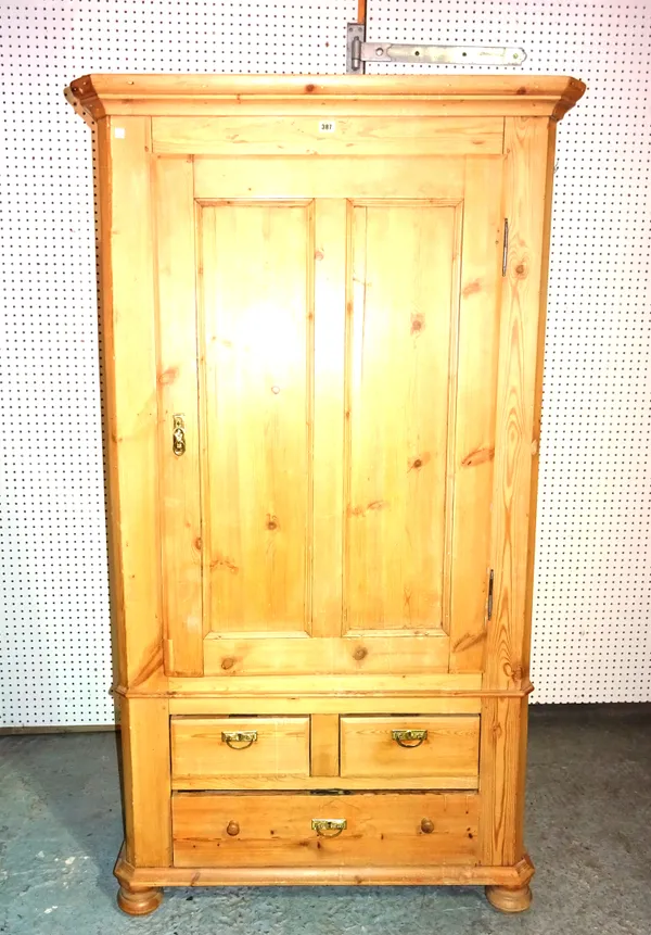 A 20th century pine single wardrobe over two short and one long drawers on bun feet, 102cm wide x 181cm  high.   M8
