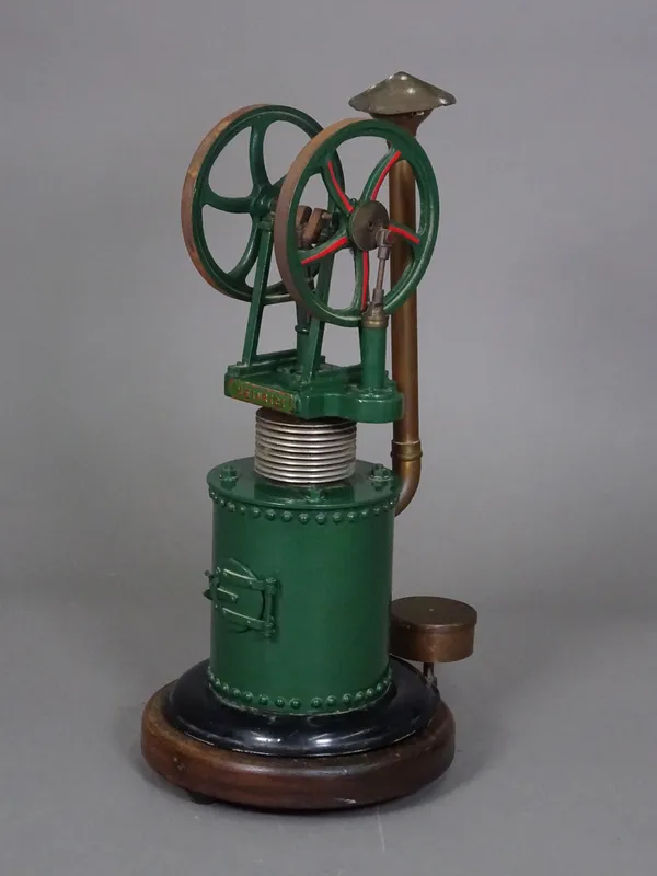 A live vertical hot air engine, green livery with title plate 'HEINRICI', copper boiler and flue on a wooden circular base, 40cm high. Illustrated.