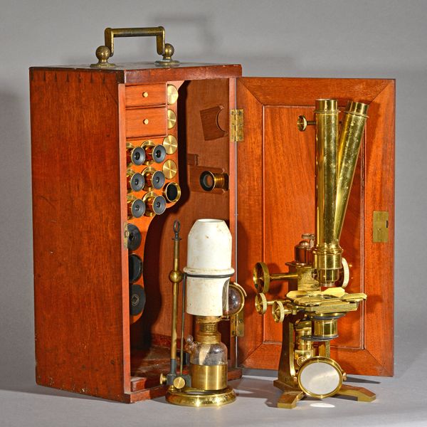 A brass binocular microscope by E.G. Wood, late 19th century, unsigned, with accessories, including a brass bullseye lens and a brass adjustable night